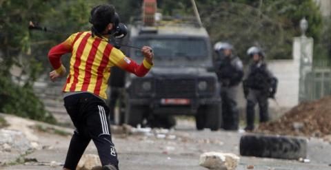 Un niño palestino tira una piedra a policías israelíes durante una protesta. REUTERS/Abed Omar Qusini
