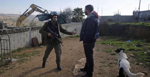Un policía israelí habla con un palestino durante la destrucción de una empalizada en Hebrón. REUTERS/Mussa Qawasma