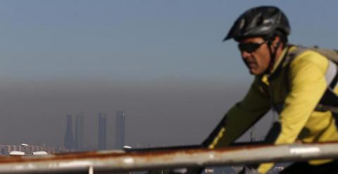 Un ciclista pasea por Pozuelo ante la boina de contaminación de Madrid. EFE