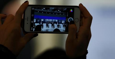 Un asistente a las conferencias del foro de Davos toma una foto con su smartphone. REUTERS/Ruben Sprich