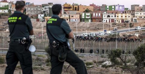 Dos agentes de la Guardia Civil vigilan la frontera de Melilla ante el intento de un grupo de personas de saltarla. AFP