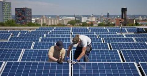 Dos operarios instalan paneles solares sobre el tejado de un edificio. EFE (Archivo)