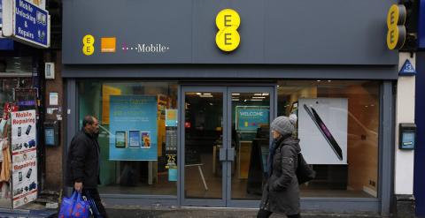 Unos peatones pasan por delante de una tienda de la operadora de telefonía móvil EE en Londres. REUTERS/Suzanne Plunkett