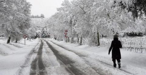 Una mujer camina por una carretera nevada en las inmediaciones de l’Espluga de Francoli (Tarragona), uno de los pueblos catalanes afectados por el temporal de nieve. / EFE