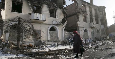 Una mujer pasea junto a un edificio derruido en Vuhlehirsk. - REUTERS