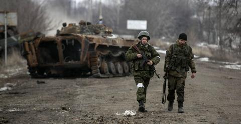 Soldados de la autoproclamada República Popular de Donetsk pasan junto a un transporte blindado ucraniano destruido en un puesto de control en la carretera de la ciudad de Vuhlehirsk a Debáltsevo. REUTERS / Baz Ratner