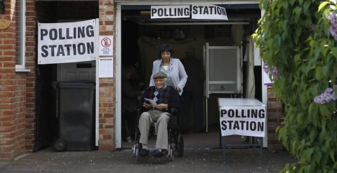 Dos personales salen de votar en una mesa electoral instalada en el garaje de una casa de Croydon. - AFP