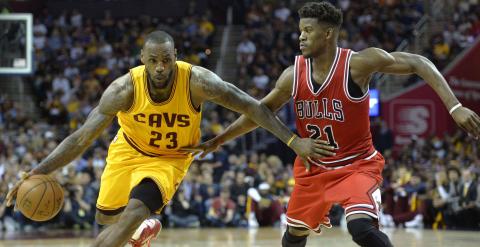 LeBron James se marcha con el balón ante la presión de Jimmy Butler. /REUTERS