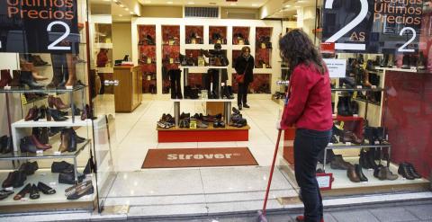 Una dependienta limpia la entrada de una tienda de calzado. REUTERS