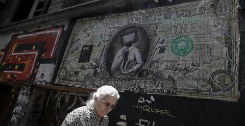 Una mujer pasa por delante de una pintada en Atenas que caricaturiza un billete de dólar. REUTERS/Alkis Konstantinidis