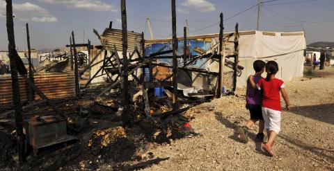 Dos niños pasan junto a los restos de campo de refugiados sirios e Líbano destruido por un incendio. Al menos seis personas murieron. - REUTERS
