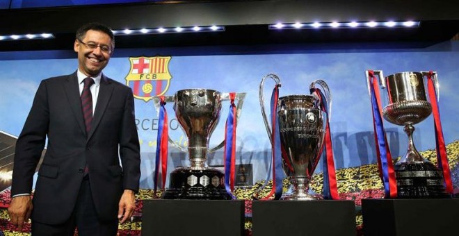 El presidente del FC Barcelona, Josep María Bartomeu, posa con los trofeos de la Liga, Liga de Campeones y Copa del Rey al finalizar su comparecencia. /EFE