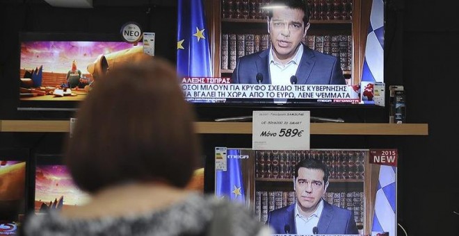 Una mujer observa en una tienda en Atenas el discurso televisado del primer ministro griego, Alexis Tsipras. - EFE