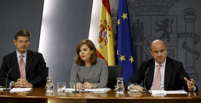 La vicepresidenta del Gobierno Soraya Sáenz de Santamaría junto a los ministros de Justicia, Rafael Catalá, (iz),y Economía, Luis de Guindos. /EFE