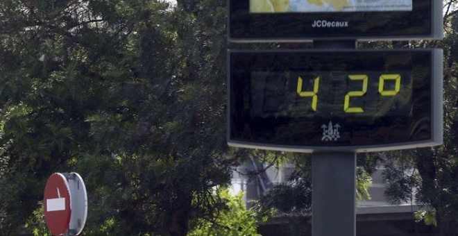 Unos turistas pasan junto a un termómetro por el centro de Córdoba que se encuentra en alerta amarilla por altas temperaturas. EFE/Salas