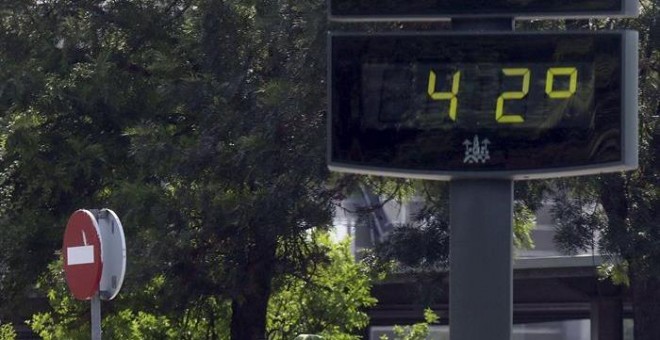 Unos turistas pasan junto a un termómetro por el centro de Córdoba que se encuentra en alerta amarilla por altas temperaturas. EFE/Salas