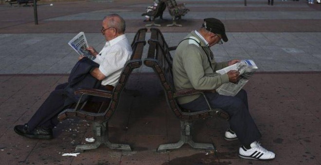 Dos pensionistas leen el periódico en un banco en Madrid. REUTERS