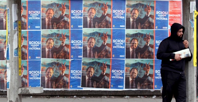 Un hombre en una parada de autobús junto a los carteles que anuncian el candidato presidencial Scioli en La Matanza, Argentina. REUTERS / Marcos Brindicci