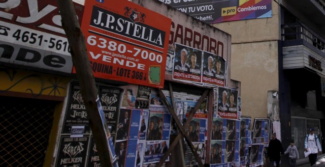 La gente camina debajo de un banner de publicidad del candidato presidencial Scioli y del candidato presidencial de Macri en La Matanza . REUTERS / Marcos Brindicci