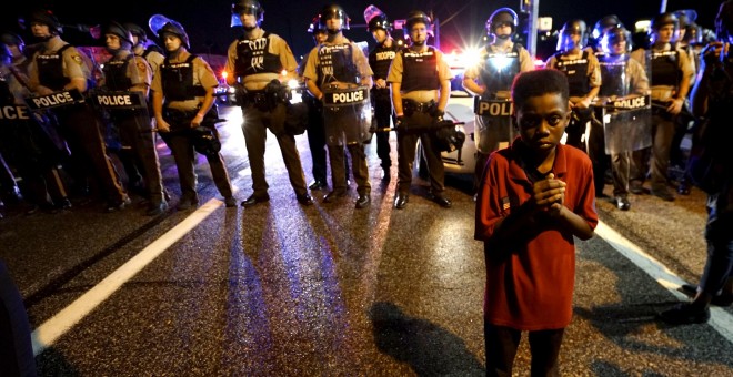 Amarion Allen, de 11 años, se sitúa frente la policía poco antes de que un policia disparase a unos manifestantes en Ferguson, Missouri, anoche, 9 de agosto 2015. Dos personas fueron disparadas en medio de un enfrentamiento nocturno entre los antidisturbi