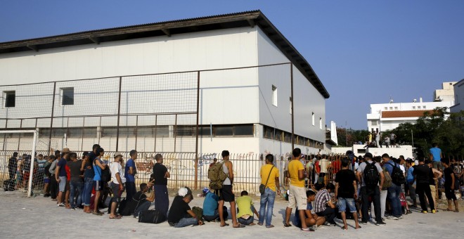 Refugiados sirios hacen cola para poder entrar en el estadio de la isla griega de Kros. REUTERS/ Yannis Behrakis