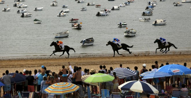 Jinetes cabalgan durante una tradicional carrera por la playa de Sanlúcar de Barrameda, en el sur de España, 12 de agosto de 2015. REUTERS / Marcelo del Pozo