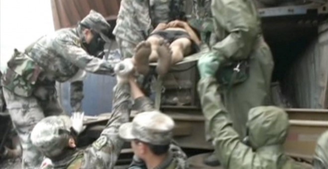 Soldados llevan a un superviviente en el almacén portuario de Tianjin (China)./ REUTERS