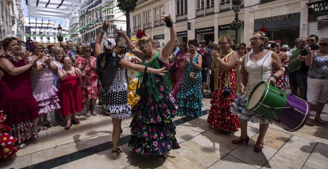 Un grupo de mujeres ataviadas con trajes flamencos tocan y bailan en la popular calle Larios de la Feria malagueña. EFE/Jorge Zapata
