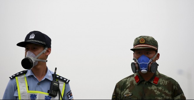 Un policía y un policía paramilitar se protegen de la contaminación con máscaras antigas. REUTERS