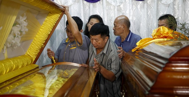 Un herido en el atentado del lunes en Bangkok, junto a los ataúdes de su esposa e hijo, muertos en la explosión.- REUTERS / Olivia Harris