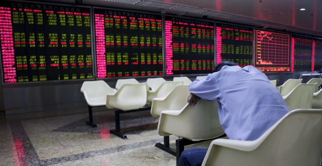 Un inversor echa una cabezada frente a un panel electrónico que muestra información de los mercados en una firma de broke ren Pekín. REUTERS/Jason Lee