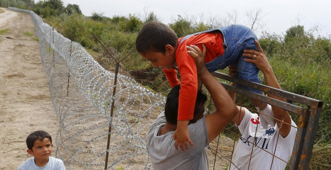 Refugiados kurdos sirios pasan un niño sobre una cerca en la frontera húngaro-serbia, cerca Ásotthalom, Hungría .- REUTERS / Laszlo Balogh