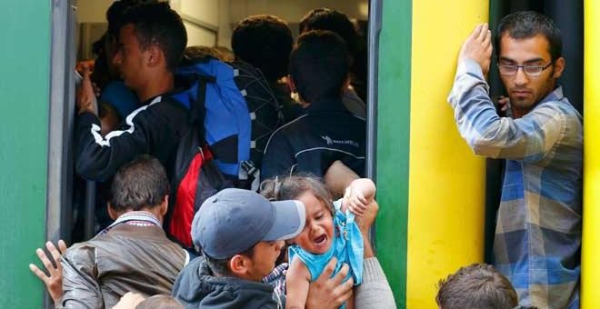 Variso refugiados sirios intentan subirse a un tren en la estación de Budapest. / LAZSLO BALOGH (REUTERS)