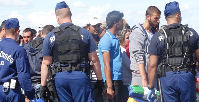 La policía rodea a los refugiados que acaban de cruzar la frontera. / CORINA TULBURE