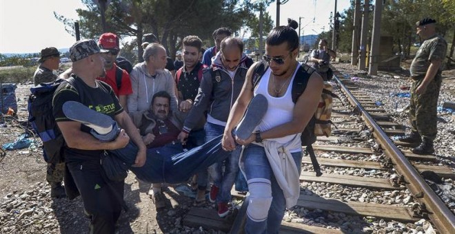 Un grupo de refugiados atraviesan la frontera entre Grecia y Macedonia, auxiliando a otro migrante. La mayoría proceden de Siria y atraviesan el autodenominado 'corredor de los Balcanes'. EFE/EPA/GEORGI LICOVSKI