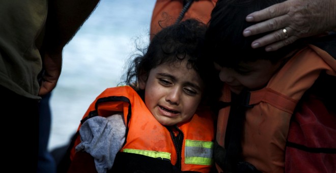 Una niña siria refugiada es abrazada por su hermano mientras llora, momentos después de llegar a un bote en la isla griega de Lesbos. REUTERS
