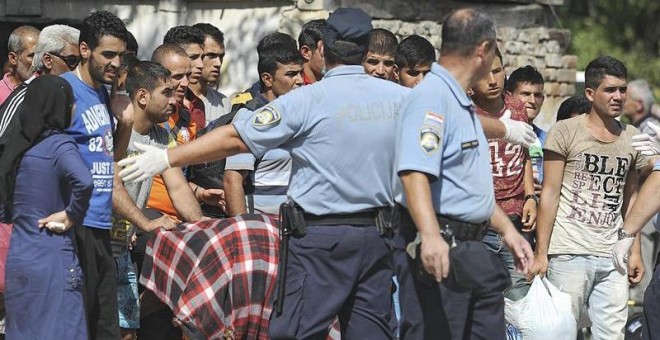 Policías croatas dirigen a varios refugiados a un autobús que les trasladará a un centro de acogida, tras cruzar la frontera con Serbia. - EFE