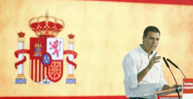 Pedro Sánchez con la bandera rojigualda durante el acto. EFE/Andreu Dalmau