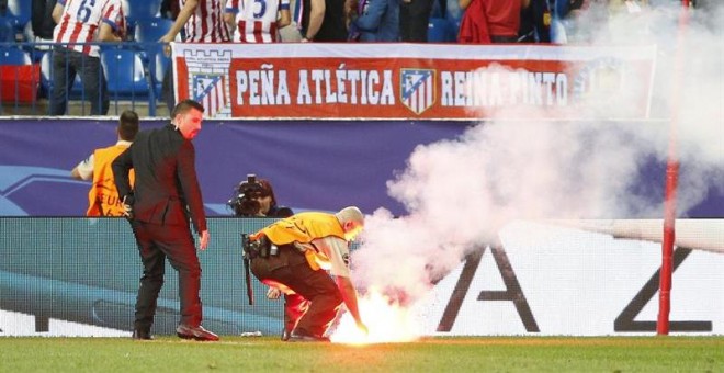 Un operario retira una de las bengalas lanzadas por hinchas del Benfica en el partido de anoche. /EFE