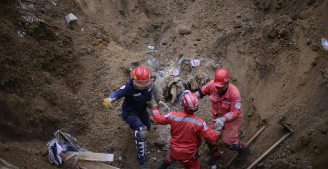 Un grupo de bomberos huye este sábado de una derrumbe de tierra  durante la búsqueda de los 350 desaparecidos de una aldea de Guatemala, sepultada por el deslave de un cerro. EFE/Esteban Biba