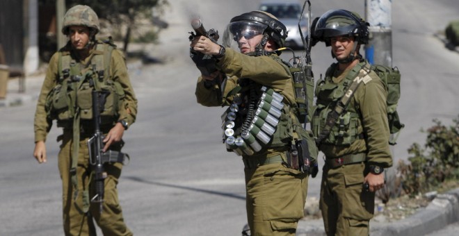 Un militar israelí lanza gases lacrimógenos para sofocar una protesta de palestinos en Hebrón. - REUTERS