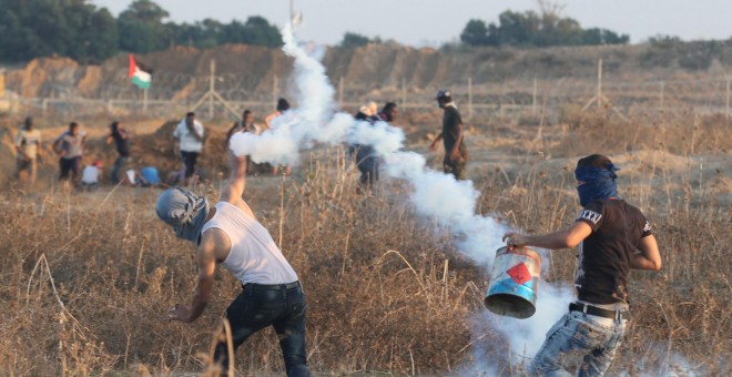 Manifestantes palestinos lanzan piedras contra la valla israelí en Gaza.-REUTERS