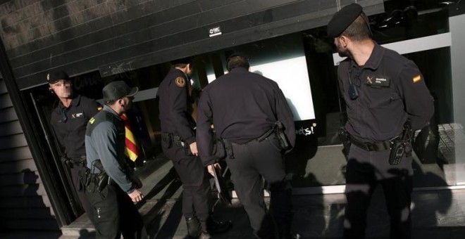 Agentes ante la fachada de la sede de CDC en Barcelona registrada./ EFE