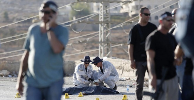 Varios policías israelíes recopilan pruebas junto al cuerpo sin vida de un palestino que ha sido abatido a tiros por un soldado israelí tras apuñalar a una joven en el asentamiento de Adam el martes. EFE