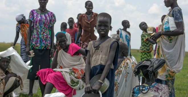 Mujeres y niños desplazados esperan una ración de comida proporcionada por el Programa Mundial de Alimentos. - AFP