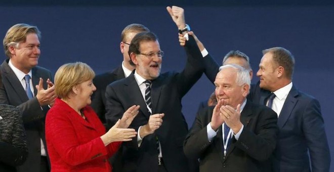 El presidente del Consejo Europeo, Donald Tusk (d), levanta el brazo del presidente del Gobierno, Mariano Rajoy (c), junto al presidente el PPE, Joseph Daul (2d), y la canciller alemana, Angela Merkel (2i), mientras posan para la foto de familia del Cong