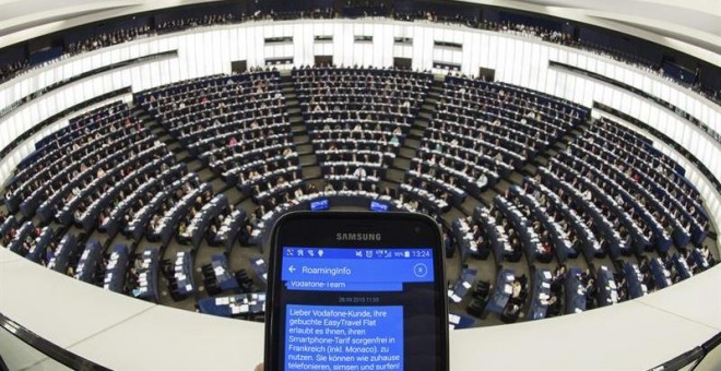 Una persona muestra un SMS con información de 'roaming' en su teléfono móvil durante el pleno del Parlamento Europeo en Estrasburgo (Francia) hoy, 27 de octubre de 2015. Los europarlamentarios votan la abolición de los recargos por el uso del teléfono móv