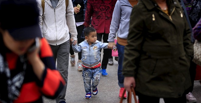 Un niño pequeño pasea de la mano de sus padres por las calles de Shanghai. REUTERS/Aly Song