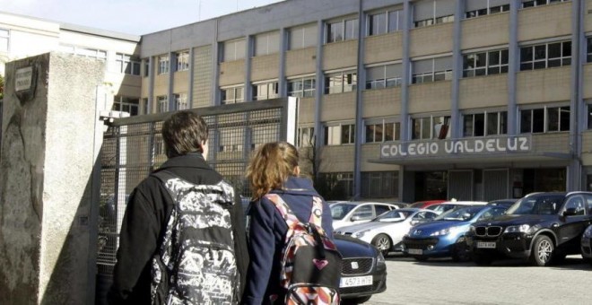 Dos jóvenes pasan por la puerta del colegio Valdeluz. /EFE