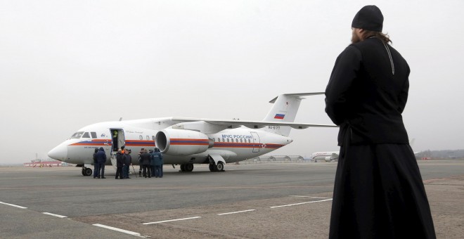 An Orthodox priest looks at a Russian emergencies ministry's plane, carrying the remains of victims of the plane crash in Egypt, shortly after its landing on the airfield of Pulkovo airport outside St. Petersburg, Russia, November 6, 2015. With world powe
